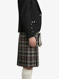 Person wearing a black blazer with silver buttons and a plaid kilt on a white background