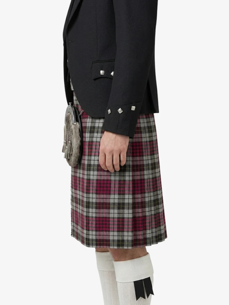 Person wearing a black jacket and plaid kilt on a white background