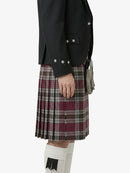 Person wearing a black jacket and plaid kilt on a white background