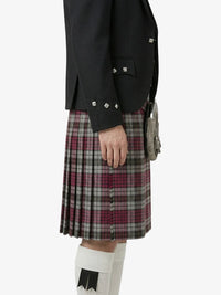 Person wearing a black jacket and plaid kilt on a white background