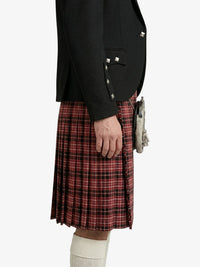 Person wearing a black jacket with silver buttons and a red plaid kilt on a white background