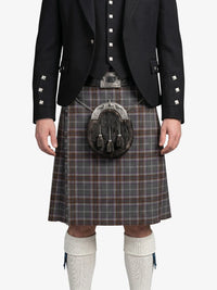 Person wearing a traditional Scottish kilt with a jacket on a white background
