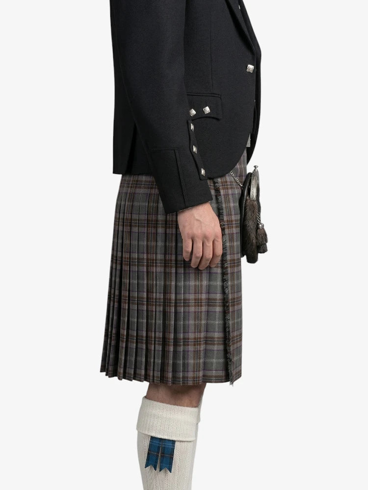 Person wearing a dark jacket and plaid kilt on a white background
