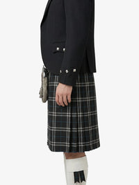 Person wearing a black jacket and plaid kilt on a white background