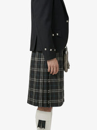 Person wearing a black jacket and plaid kilt on a white background