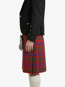 Person wearing a black jacket and red plaid kilt on a white background