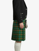 Person wearing a black blazer and green plaid kilt on a white background