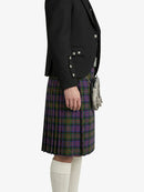 Person wearing a black blazer and plaid kilt on a white background