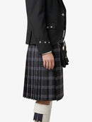 Person wearing a black jacket and plaid kilt on a white background