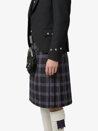 Person wearing a black jacket and plaid kilt on a white background