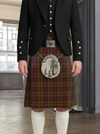 Person wearing a traditional Scottish kilt with a tartan pattern in a room with large windows.
