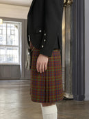 Person wearing a black jacket and plaid kilt in an indoor setting