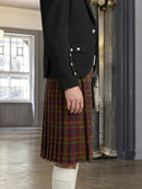 Person wearing a black jacket and red plaid kilt indoors.