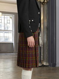 Person wearing a black jacket and red plaid kilt indoors.
