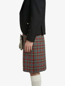 Person wearing a black jacket and plaid kilt on a white background