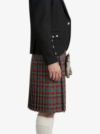 Person wearing a black blazer and plaid kilt on a white background
