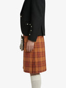 Person wearing a black jacket and orange plaid kilt on a white background