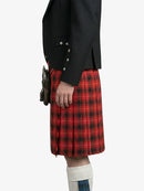 Person wearing a black jacket and red plaid kilt on a white background