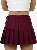 Maroon pleated skirt with black buttons worn by a person on a white background
