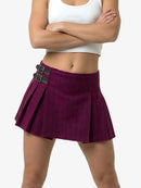 Person wearing a purple pleated skirt with black belt and white top on a white background