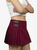 Maroon pleated skirt with silver buckles worn by a person on a white background