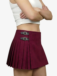 Maroon pleated skirt with silver buckles worn by a person on a white background