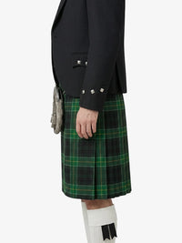 Person wearing a black jacket and green plaid kilt on a white background