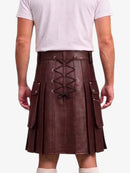 A man wearing a dark brown faux-leather kilt with a lace-up back, side pockets, and pleated front panels, paired with a white t-shirt and white socks.