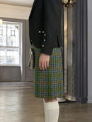 Person wearing a black jacket and green plaid kilt in an indoor setting.