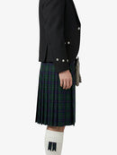 Person wearing a black jacket and green plaid kilt on a white background