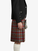 Person wearing a black blazer and red plaid kilt on a white background