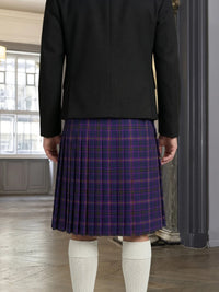 Person wearing a black jacket and purple plaid skirt indoors.