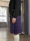 Person wearing a black jacket and purple plaid kilt indoors.