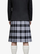 Person wearing a black coat, plaid kilt, and white knee-high socks on a white background