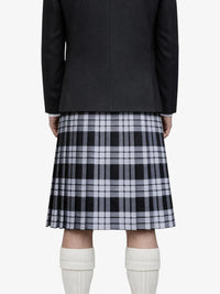 Person wearing a black coat, plaid kilt, and white knee-high socks on a white background