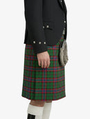 Person wearing a black jacket and green plaid kilt on a white background