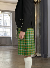 Person wearing a black jacket and green plaid kilt in an indoor setting.
