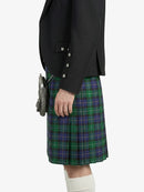 Person wearing a black blazer and green plaid kilt on a white background