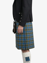 Person wearing a black jacket and blue plaid kilt on a white background