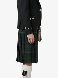 Person wearing a black jacket and green plaid kilt on a white background