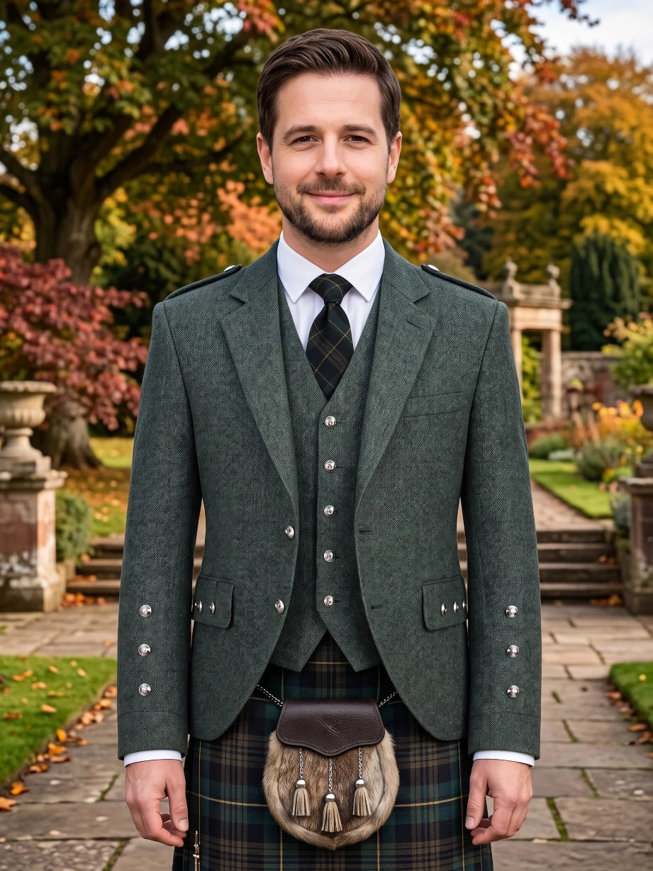 A man wearing a traditional Scottish formal outfit, featuring a dark green tweed blazer with silver buttons, a matching waistcoat, a white shirt, a black patterned tie, and a tartan kilt with a brown sporran, standing in a garden setting.