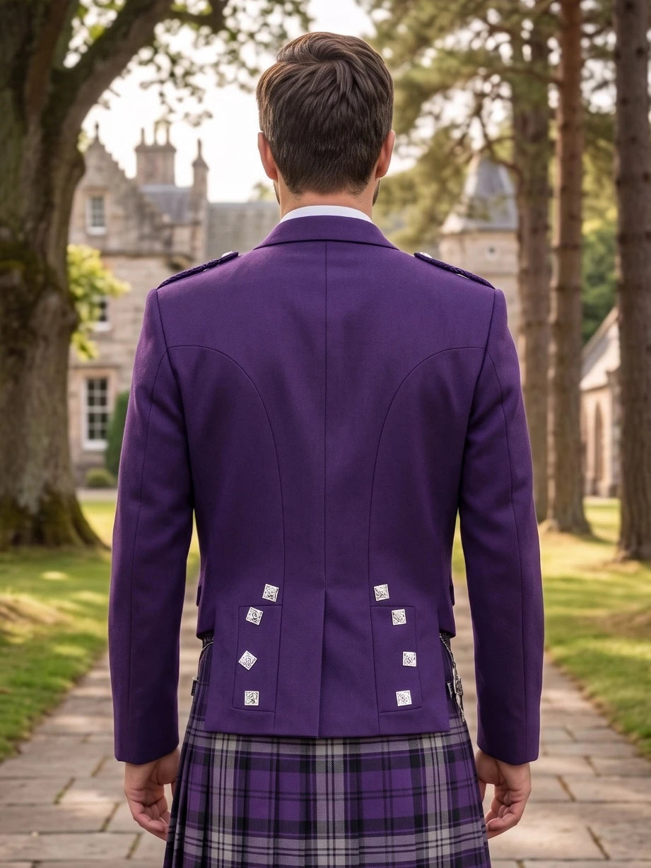 A man viewed from behind wearing a purple Scottish kilt jacket with silver buttons and a purple plaid kilt, standing on a stone path in front of a large stone castle.