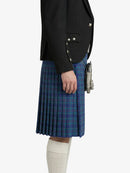 Person wearing a black blazer and blue plaid kilt on a white background