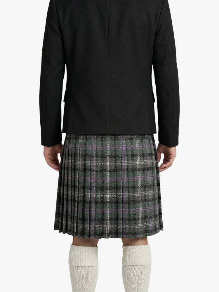 Person wearing a black jacket and plaid kilt on a white background
