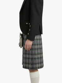 Person wearing a black blazer and plaid kilt on a white background