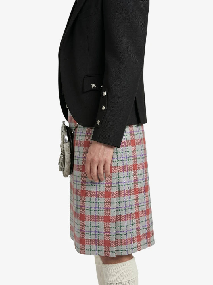 Person wearing a black blazer and plaid kilt on a white background