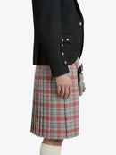 Person wearing a black jacket and plaid kilt on a white background