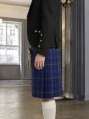 Person wearing a black jacket and blue plaid kilt indoors.