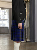 Person wearing a black jacket and blue plaid kilt indoors.
