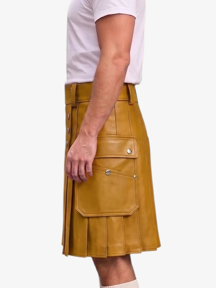 A mustard yellow faux-leather kilt with silver snap button details, shown on a model wearing a white t-shirt against a light gray background.